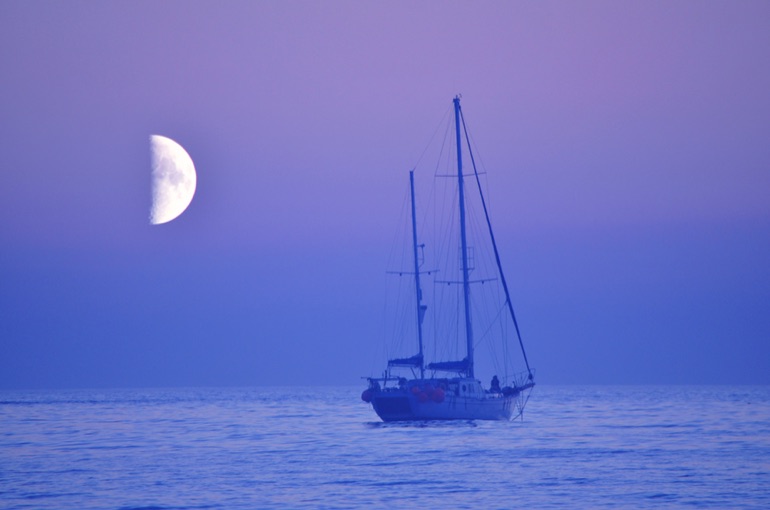 Yacht sailing under a moon